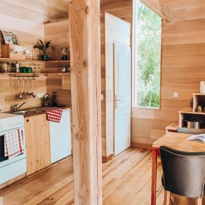Cabane en bois moderne avec cuisine équipée et coin salon lumineux.