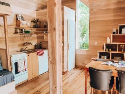 Cabane en bois moderne avec cuisine équipée et coin salon lumineux.