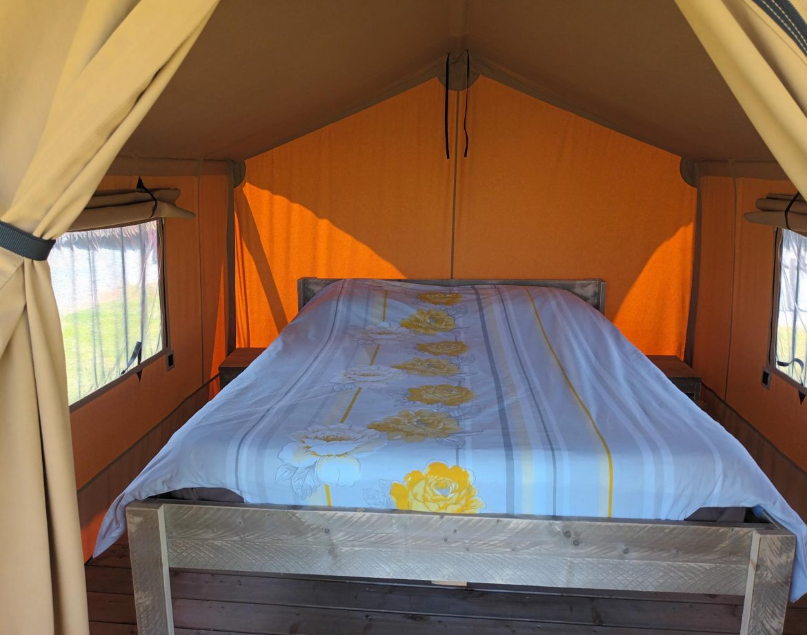 Tente safari confortable avec un lit douillet et des murs orange lumineux.