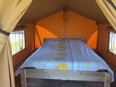Tente safari confortable avec un lit douillet et des murs orange lumineux.