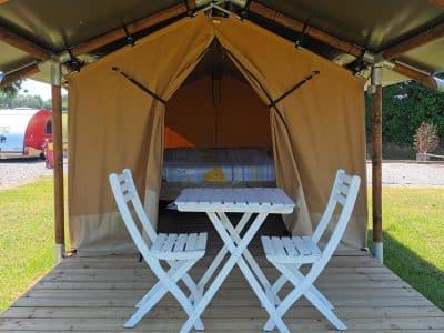 Tente safari cosy avec terrasse en bois et mobilier blanc dans le Pays de la Loire.