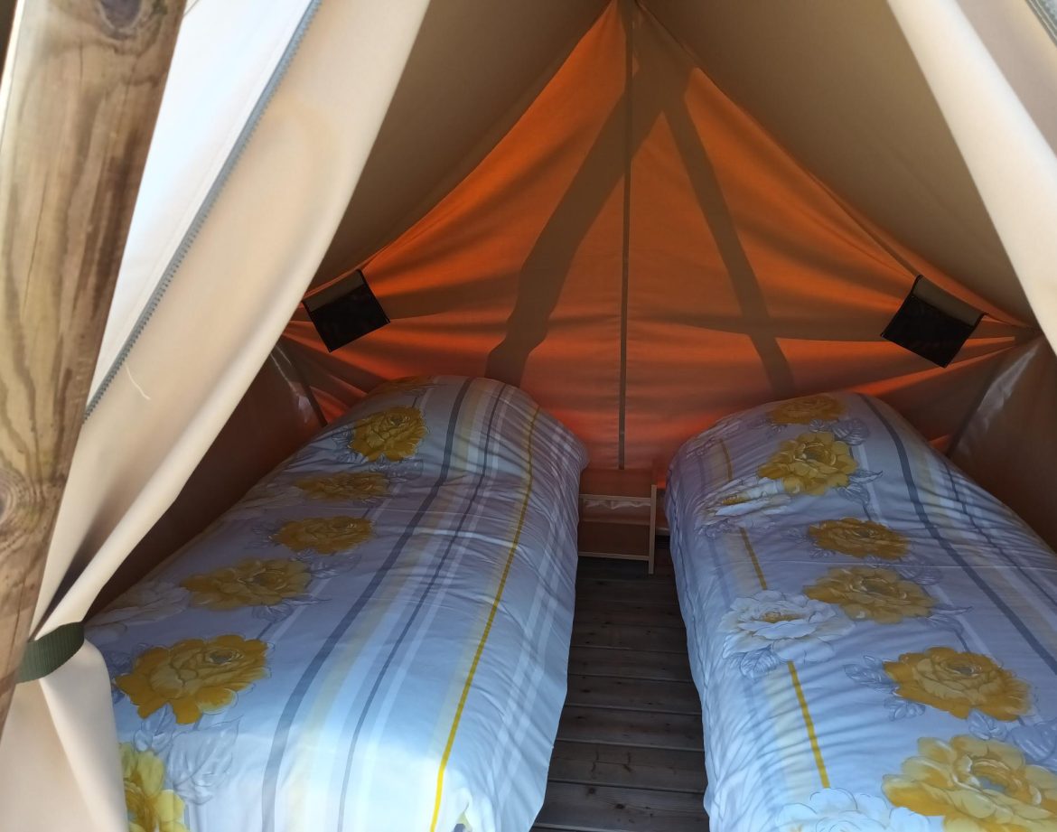 Tente safari confortable avec lits à fleurs, idéale pour un séjour insolite en Pays de la Loire.