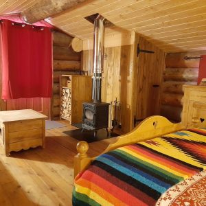 Cabane en bois avec poêle à bois et décoration colorée, idéale pour un séjour chaleureux.