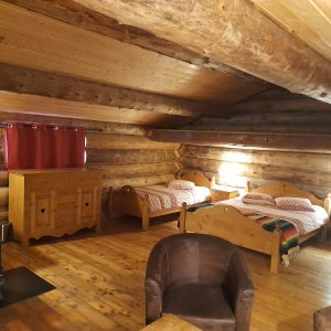 Chalet en bois chaleureux avec lits en bois et poêle à bois, idéal pour un séjour cocooning.