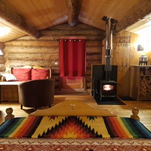 Cabane en bois chaleureuse avec un poêle à bois et des décorations colorées.