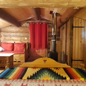 Chalet en bois chaleureux avec un poêle à bois et des meubles en bois rustiques.