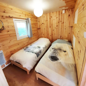 Chalet en bois avec lits jumeaux, décoré de couettes à motif ours polaire.