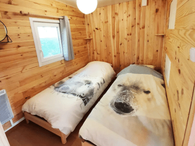 Chalet en bois avec lits jumeaux, décoré de couettes à motif ours polaire.