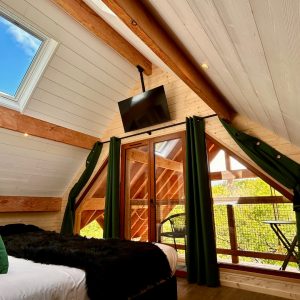 Chalet en bois avec vue sur la nature, lit confortable et balcon lumineux.