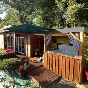 Cabane en bois avec jacuzzi extérieur, entourée de verdure à Aquitaine.