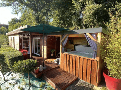Cabane en bois avec jacuzzi extérieur, entourée de verdure à Aquitaine.