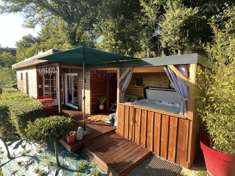 Cabane en bois avec jacuzzi extérieur, entourée de verdure à Aquitaine.