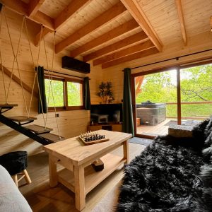 Cabane en bois avec intérieur chaleureux, vue sur la nature et jacuzzi extérieur.