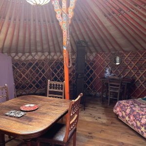 Yourte accueillante en Midi-Pyrénées, avec un intérieur en bois et des décorations colorées.