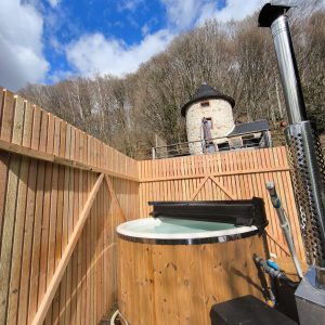 Hébergement insolite en Midi-Pyrénées avec un jacuzzi en bois et une tour en pierre.