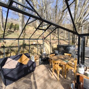 Hébergement insolite en véranda avec mobilier en bois et vue sur la nature.