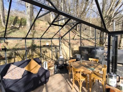 Hébergement insolite en véranda avec mobilier en bois et vue sur la nature.