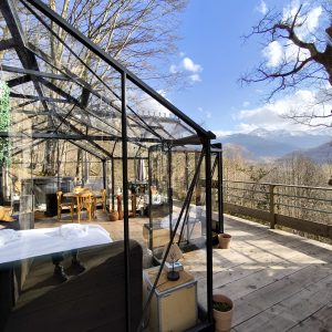 Hébergement insolite en verre avec vue sur les montagnes, entouré darbres.