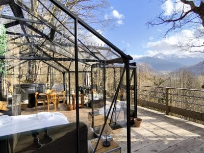 Hébergement insolite en verre avec vue sur les montagnes, entouré darbres.