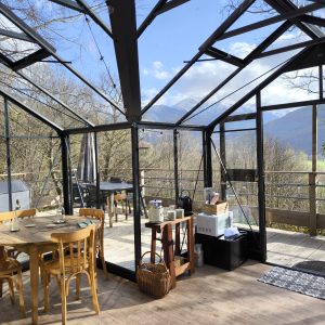 Hébergement insolite en véranda, avec vue sur les montagnes et mobilier en bois.