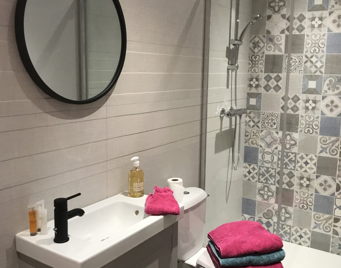 Salle de bain moderne dun hébergement insolite en Auvergne-Rhône-Alpes, avec carrelage coloré.