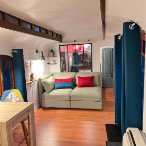 Hébergement insolite en Aquitaine : intérieur cosy avec canapé et rideaux colorés.