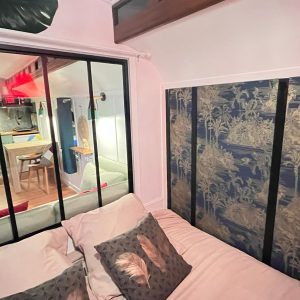 Hébergement insolite en Aquitaine : chambre cosy avec décor tropical et vue sur la cuisine.