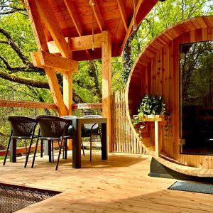 Cabane en bois avec terrasse, offrant une vue sur la nature verdoyante.