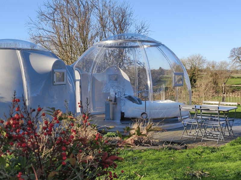 Hébergement insolite : bulles transparentes avec vue sur la nature et mobilier extérieur.