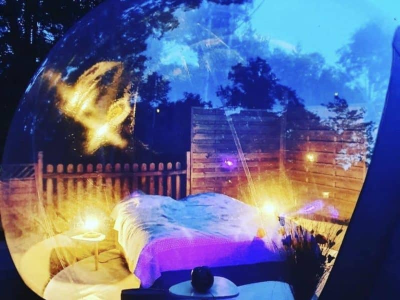Hébergement insolite en bulle transparente, lit confortable sous un ciel étoilé.