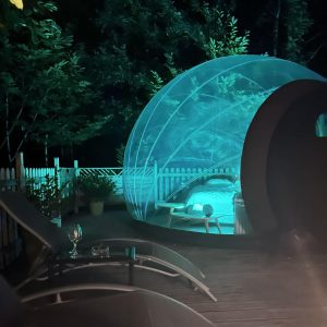 Hébergement insolite à Limousin : bulle transparente illuminée, entourée de verdure.