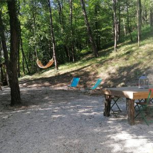 Hébergement insolite en pleine nature avec chaises longues et hamac dans les arbres.