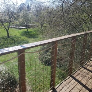 Cabane perchée en Haute-Normandie avec vue sur un jardin verdoyant.