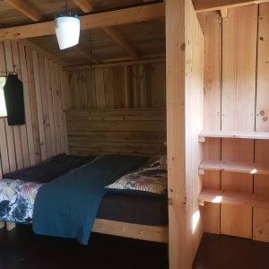Cabane en bois cosy avec lit douillet et murs en bois naturel.