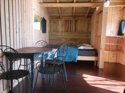Cabane en bois à Haute-Normandie, avec lit confortable et table en fer forgé.