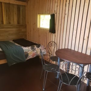 Cabane en bois à Haute-Normandie avec lit douillet et table en fer forgé.