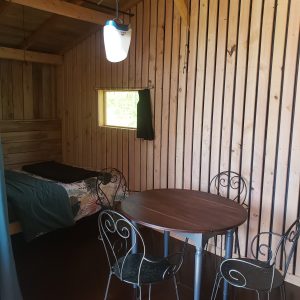 Cabane en bois à Haute-Normandie, avec lit confortable et table ronde.