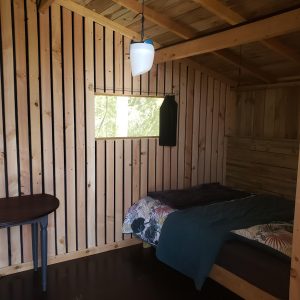 Cabane en bois à Haute-Normandie, intérieur chaleureux avec lit et table.