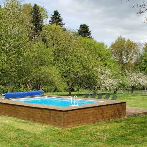 Hébergement insolite en Haute-Normandie avec piscine entourée darbres verdoyants.