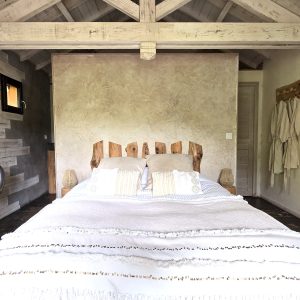Chalet en bois dans les Alpes, avec un lit douillet et des murs en pierre.