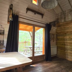 Cabane en bois dans les arbres, avec vue sur la nature et lumière naturelle.