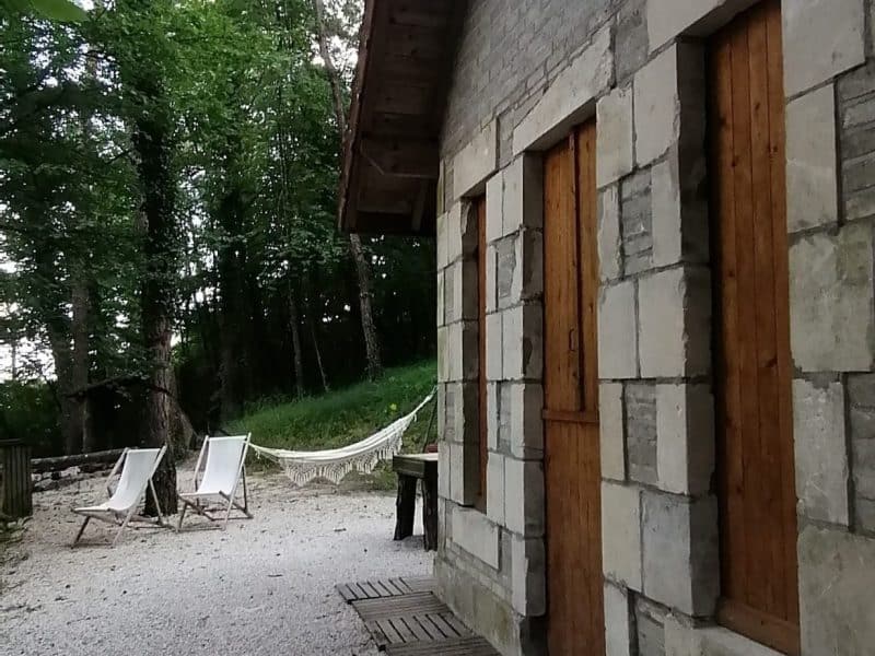 Charmante maison en pierre avec chaises longues et hamac dans un cadre verdoyant.
