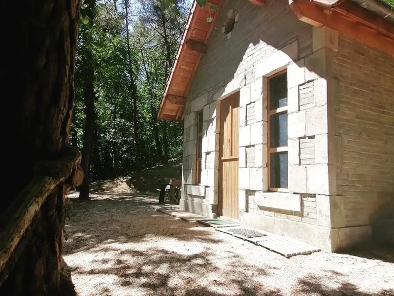 Charmante cabane en pierre, entourée darbres, avec un toit en tuiles.