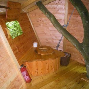 Cabane dans les arbres avec un intérieur en bois, incluant un coin toilette original.