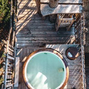 Cabane perchée en Provence-Alpes-Côte dAzur avec jacuzzi en bois sur terrasse en bois.