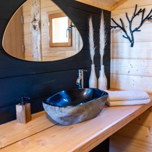 Salle de bain dun hébergement insolite en bois, avec lavabo en pierre et décor naturel.