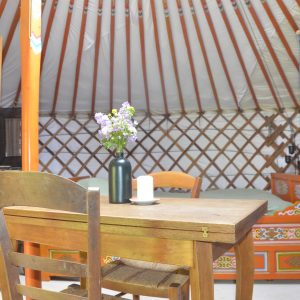 Yourte spacieuse en Midi-Pyrénées, avec table en bois et fleurs sur la table.