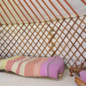 Intérieur dune yourte colorée en Midi-Pyrénées, avec un lit douillet et des murs en bois.