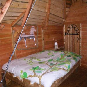 Chalet en bois avec un lit douillet, décoré de motifs naturels et ambiance chaleureuse.