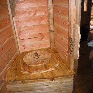 Cabane en bois avec toilettes sèches en bois, ambiance rustique et chaleureuse.